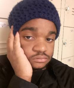 Headshot of Michael wearing a beanie and leaning against some lockers