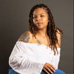 A headshot of an artist wearing a white blouse