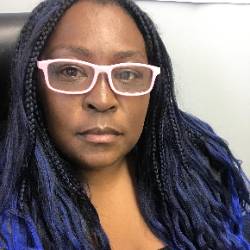 A headshot of an artist with blue braids and glasses