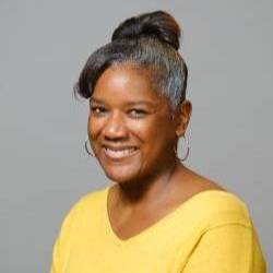 A headshot of an artist in a yellow blouse with her hair pulled back