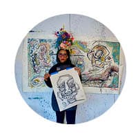 female holding her art in front of a wall with art on it