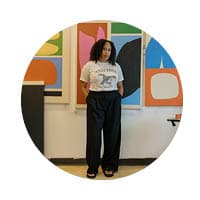 female standing in front art wall with white shirt and black pants on