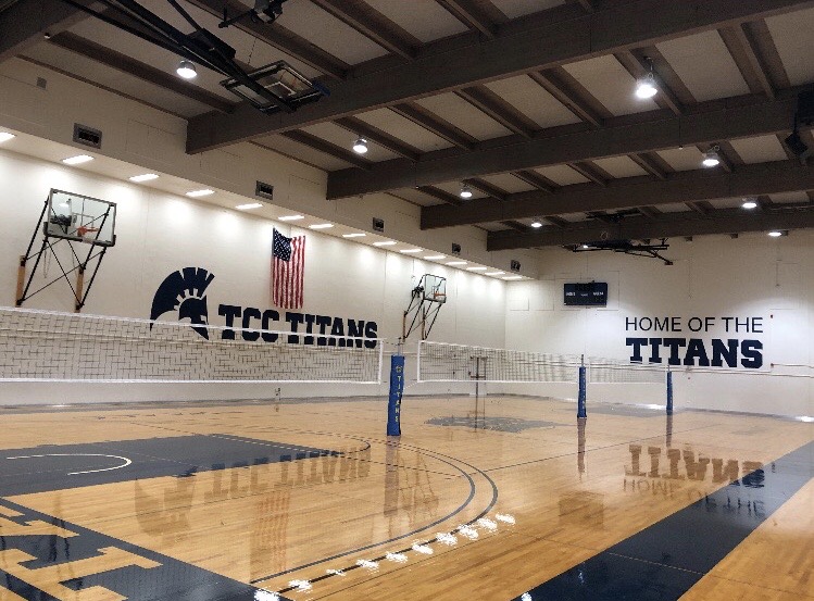 a wide shot of the auxiliary gym, picturing volleyball nets through the center