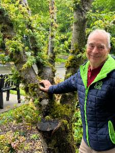 Photo of Tom Kuehne standing in front of a Japanese Maple at the Gig Harbor Campus entrance.