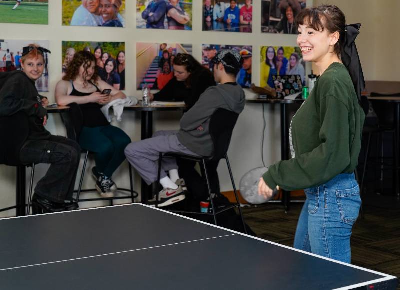 Una estudiante juega ping pong en el centro de estudiantes