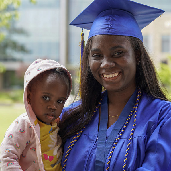 Woman in cap and gown with baby smiling