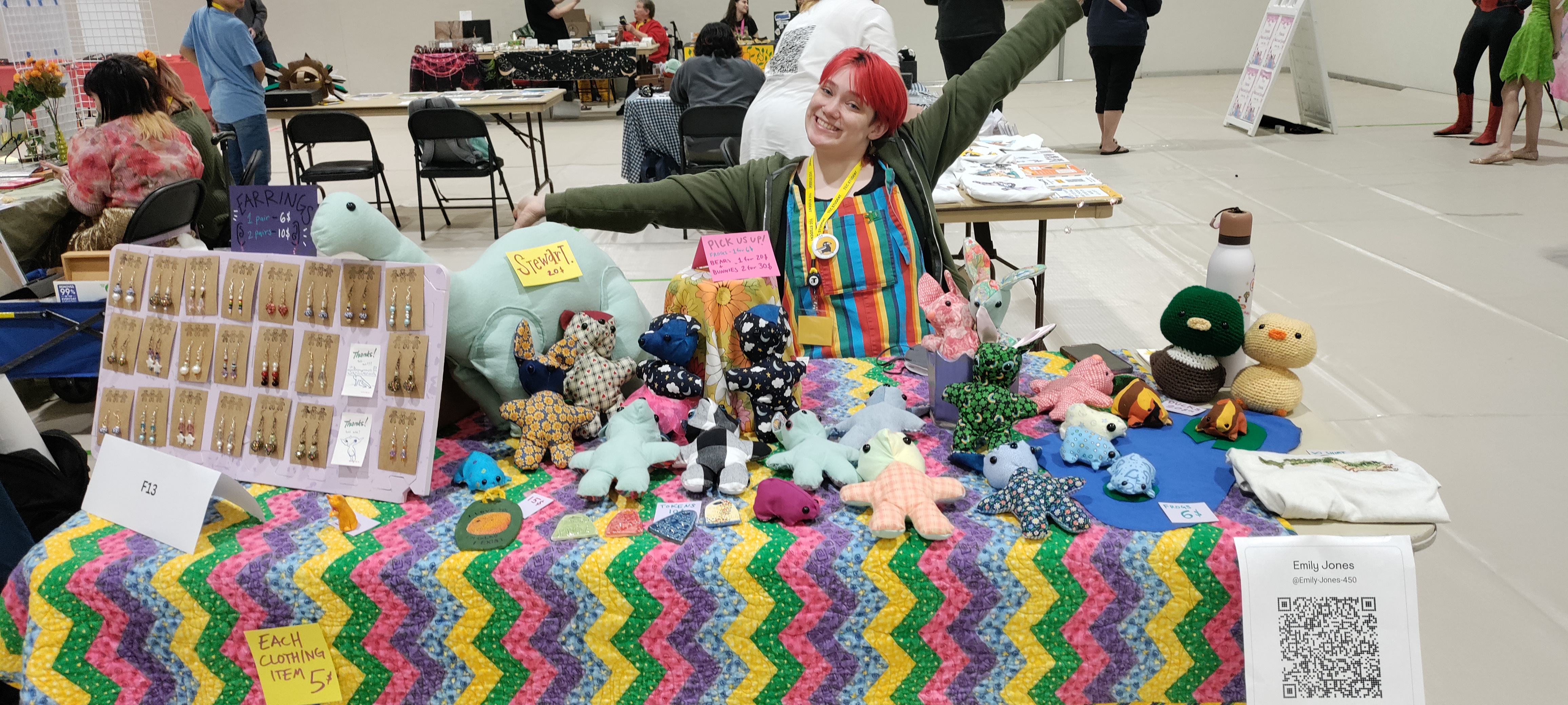 Picture of an art market vendor with a table full of art in front of her. 