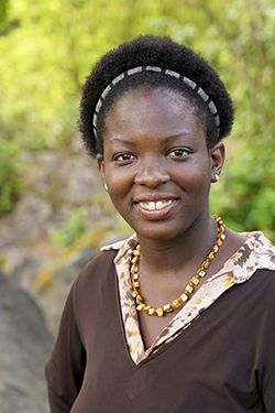 Image of a woman with short hair and a hairband wearing a brown sweater and a necklace