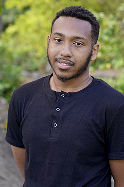 Image of a man with short hair wearing a black shirt. 