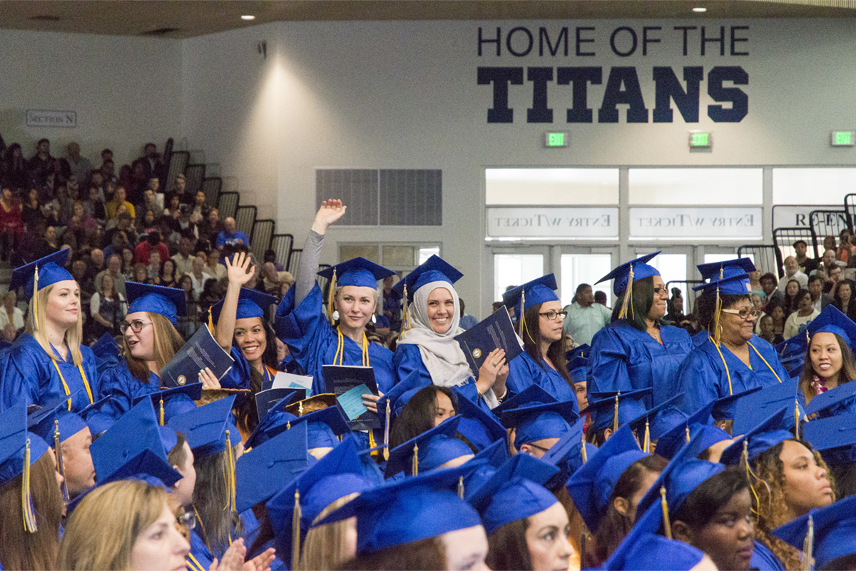 A large group of graduates under a sign that says Home of the Titans