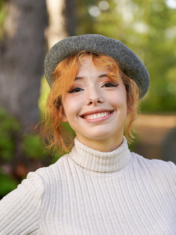 Woman wearing a white sweater and a beret smiling
