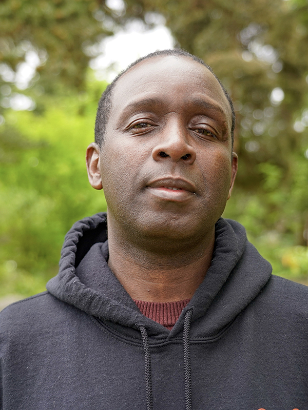 Picture of a man in a black sweatshirt smiling. 
